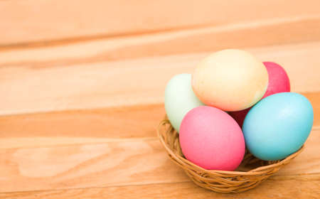 Easter eggs in a wicker basket on a wooden backgroundの写真素材