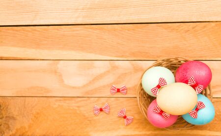 Easter eggs in a wicker basket on a wooden backgroundの写真素材