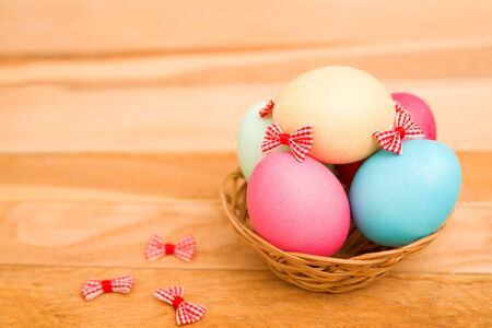 Easter eggs in a wicker basket on a wooden backgroundの写真素材
