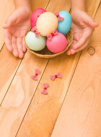 Easter eggs in a wicker basket on a wooden backgroundの写真素材
