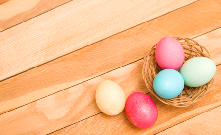 Easter eggs in a wicker basket on a wooden backgroundの写真素材