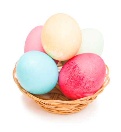 Easter eggs in a wicker basket on a white backgroundの写真素材
