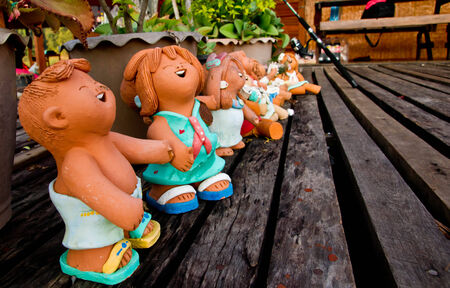 Thailand stucco children sitting on old wooden floor.の写真素材