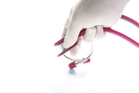 Hand has surgical gloves hold red stethoscope is white bacgroundの写真素材