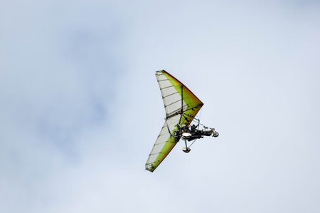 A white and yellow glider flying in the sky with two drivers