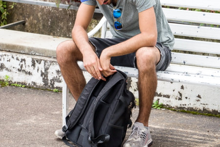 man sitting on a white chair holding a backpack