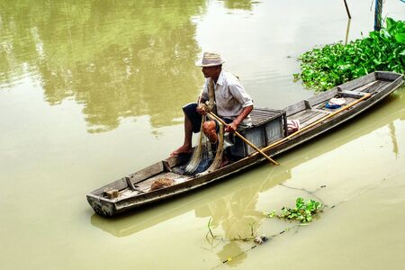 A fisherman on a boat in the riverの素材