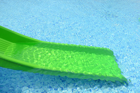 green plastic slider in front of swimming pool