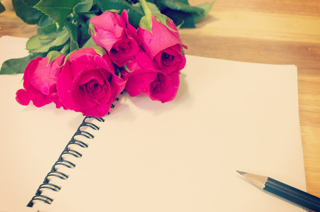 Vintage,retro of note book paper and pencil with roses on wooden background soft focus.の写真素材