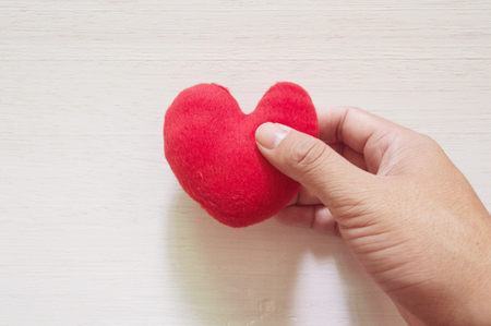Hand picking  heart on the white wooden backgroundの写真素材