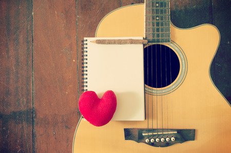 Notebook and wooden pencil with heart on guitar,Writing music filtered effectの写真素材
