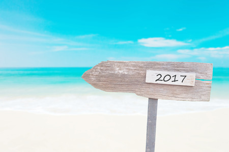 Wooden Blank Sign With Text 2017 , Over Blurred blue sea and sand beach with Cloudy Blue Sky , Image for New year 2017 Concept.の写真素材