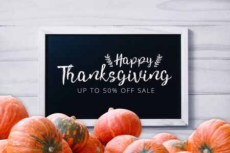 Thanksgiving promotion banner on  blackboard on wood white background with stack of pumpkins greeting seasonの写真素材