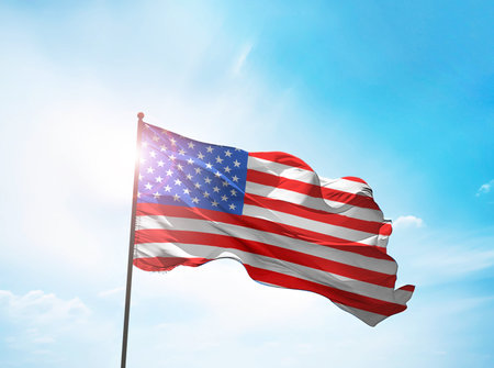 American flag on the blue sky with sunlightの写真素材