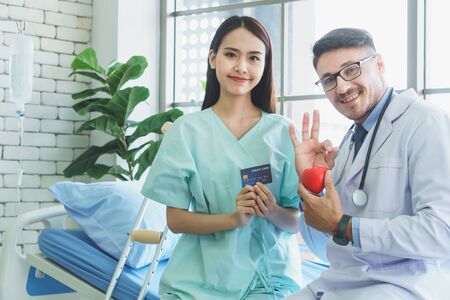 Photos of a male doctor taking care of a female patient and providing health care advice In the patient room of the hospital ( Mockup CREDIT CARD )の写真素材
