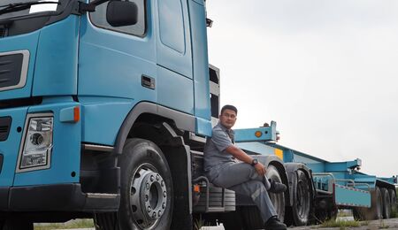 Asian young man Is a truck driver in the transportation business Equipped with large blue trucks Parking a car on the side of the roadの写真素材