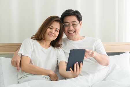 Asian Old Couple Using a laptop and credit card In online shopping at home Happily in the morning.の写真素材