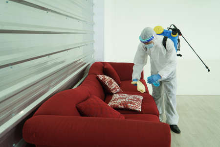 Workers wear protective clothing and wear a mask. Spraying disinfectants for cleaning inside the...