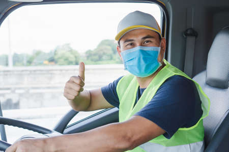 Professional worker, truck driver, middle-aged Asian man wearing protective mask And safety vests...