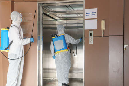 Professional  male worker In protective clothing and masks are spraying disinfectants, cleaning,...
