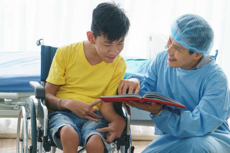 Asian doctors, adult men talking to patients with boy disabled in wheelchairs. Counseling and...