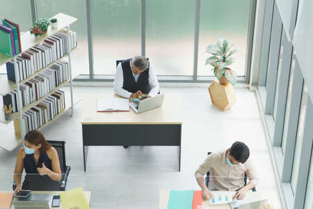 Multi-ethnic business group Wears masks for protection against coronavirus and air pollution. Work together in the office. Social distancing is a new normal concept for employee safety in the company.の写真素材
