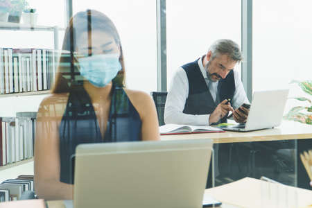 Business people wear a protective mask to work together in the company office. social distancing is...