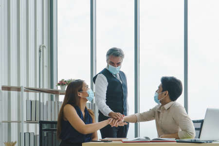 Business people wear a protective mask to work together in the company office. social distancing is...