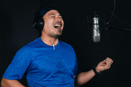 Confident Asian mature young man and a microphone Practice singing in the recording studio. Artist...