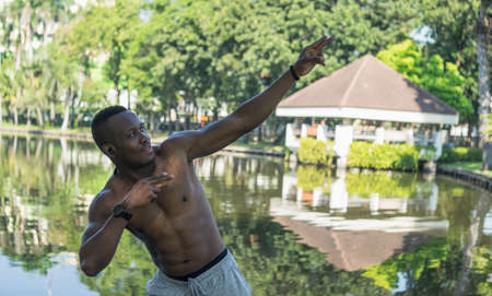 African American young man exercising outdoors. muscular young man stretching in green forest park....