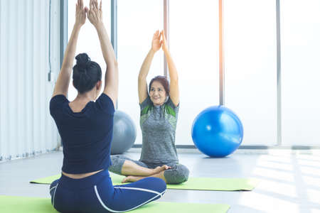 Happy smiling healthy middle-aged woman practicing yoga in sports club with her growing daughter.Fitness, stretching group of women, housewives love health, exercise for relaxation, and life balance.の写真素材