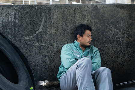 homeless poor Asian man have a fever sleeping by the wall. young male with beard unemployment...