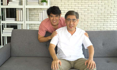 Portrait Asian family happy smiling senior father and grown-up son at home. young man cuddling...