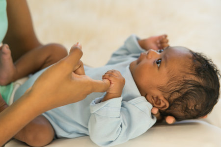 African Newborn baby one-month-old holding fingers mother's hand, Smile and look relax worry-free. image with a shallow depth of field, Select the focus area of the hand.の写真素材