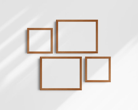 Set of four wooden frames on a white wall with shadows. Clean, modern, and minimalist wall art mockup. Frame mockup. Set of two horizontal frames and two square frames.の写真素材