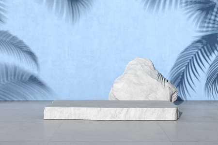 3D rendering of white stone podium for product presentation on blue concrete wall with palm leaf shadow.の写真素材
