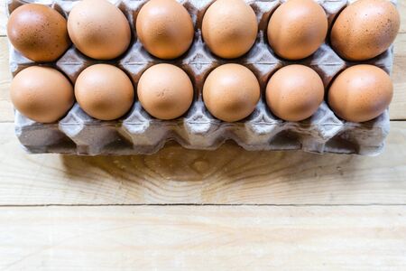 Top view eggs in paper panel on wooden table with copy space