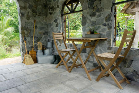 Empty wooden table and chairs with stone living room in the gardenの写真素材