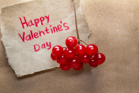 Happy Valentine's Day card handmade with heart and red viburnum on the background of kraft paperの写真素材