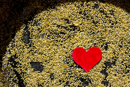 Happy Valentine's Day card with heart handmade on the background of yellow corn gritsの写真素材