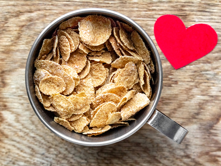 Top view of corn flakes, cereal breakfast in a metal container on a wooden background heart foodの写真素材