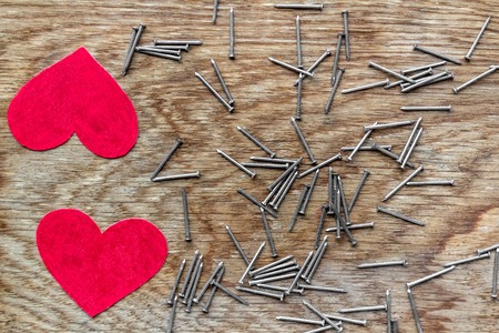 two love hearts on wooden background surrounded by iron nailsの写真素材