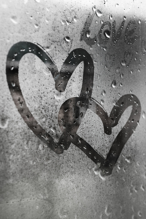two connected hearts painted on glass in Rainy weather there are many drops on itの写真素材