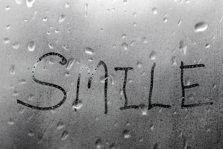 Handmade word smile on the wet glass windowの写真素材