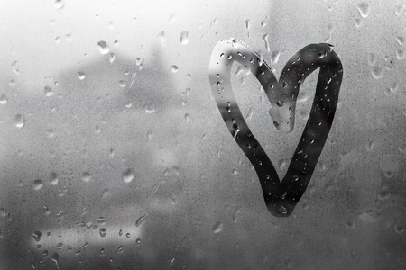 Heart painted on glass in Rainy weather there are many drops on itの写真素材