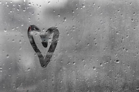 Heart painted on glass in Rainy weather there are many drops on itの写真素材