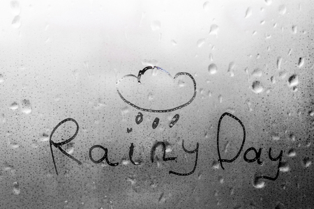 The word RAINY DAY written and drawn cloud on the wet glass rainの写真素材