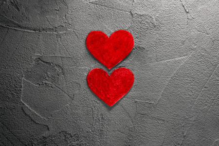 two red paper hearts on gray wallの写真素材
