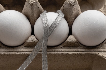 chicken eggs in a paper tray on background with silver Easter ribbonの写真素材