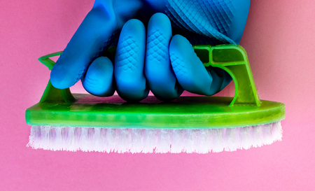 spring cleaning, bright colors, a beautiful hand with a blue glove holding a green brush on a pastel background, advertising cleaning agents, chemical cleaning agents, health careの写真素材